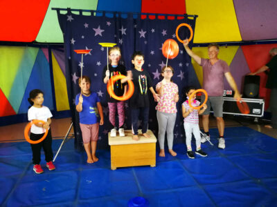 Kinder posieren mit Michael Behrens im Zirkuszelt