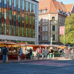 Samstäglicher Wochenmarkt auf dem Lindener Marktplatz mit Marktständen. Im Hintergrund das Lindener Rathaus und der Türmer-Brunnen.