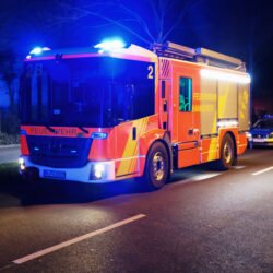 Hilfeleistungslöschgruppenfahrzeug der Feuerwehr Hannover bei Nacht mit Blaulicht auf der Straße stehend
