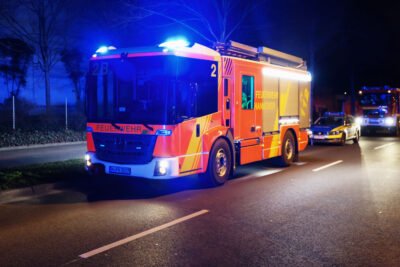 Hilfeleistungslöschgruppenfahrzeug der Feuerwehr Hannover bei Nacht mit Blaulicht auf der Straße stehend